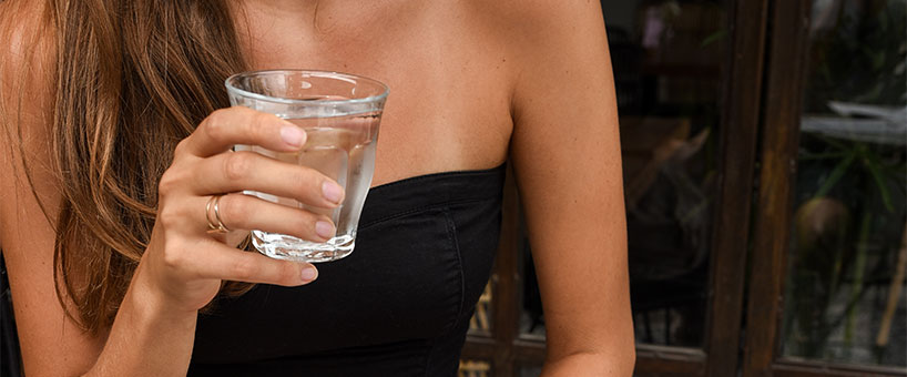 bere acqua in un bicchiere di vetro trasparente